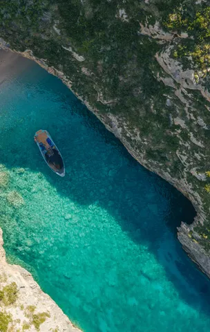 Aerial view of a boat in a turquoise cove on the Albanian Riviera